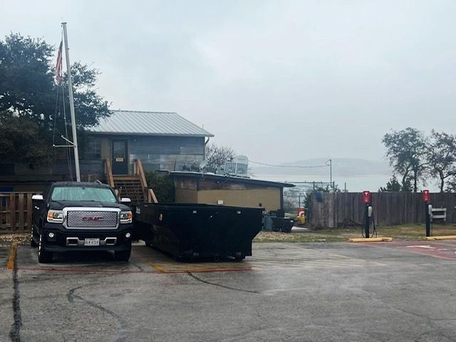 A gmc truck is parked in a parking lot next to a dumpster.