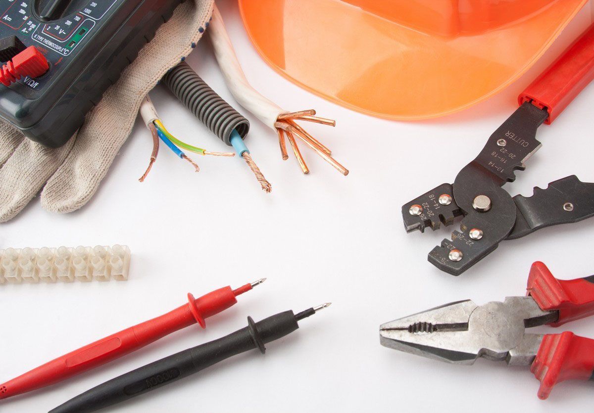 Electrician tools, wires, and pliers on a white background with an orange hard hat