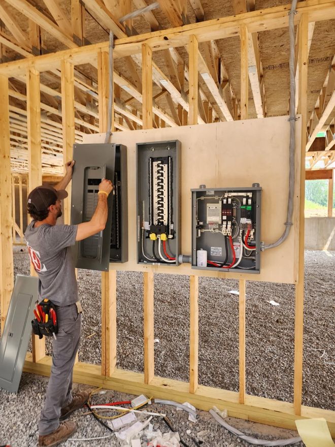 Person installing a ceiling light fixture with exposed wires, reaching upward indoors.