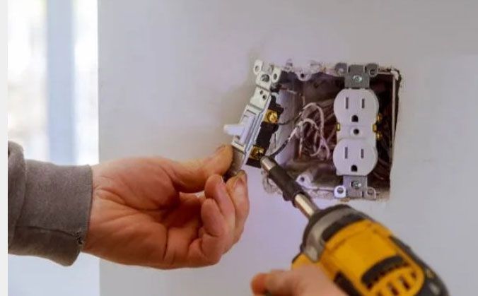 Hand wiring an electrical outlet box with a screwdriver and drill