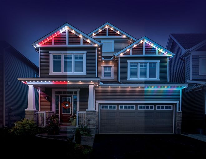 Two-story suburban house at night, outlined with colorful holiday string lights.