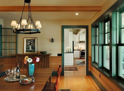 Dining room with wooden table, colorful flowers, chandelier, and a view into the kitchen.