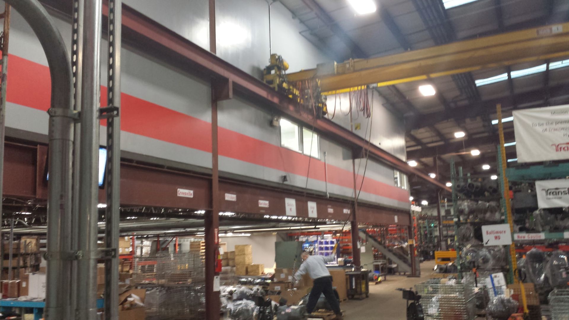 Inside a warehouse-style store, tall shelving and stacked goods line a busy industrial interior.