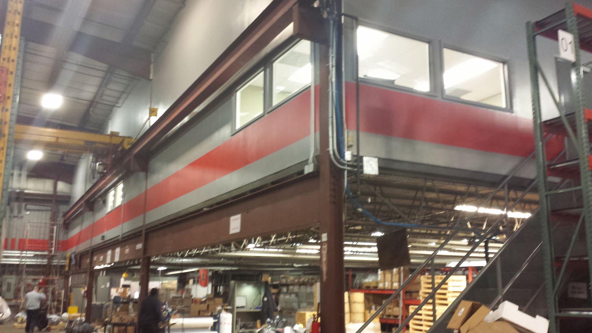 Elevated industrial office walkway with red and gray walls inside a warehouse-like factory.