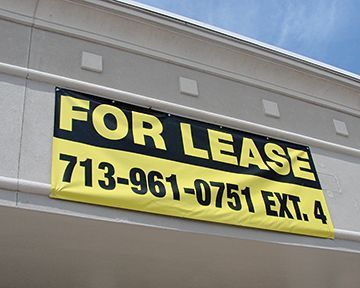 A for lease sign hangs on the side of a building