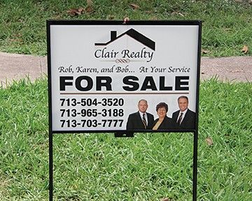 A for sale sign for clair realty is in the grass