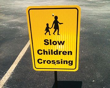 A yellow sign that says slow children crossing
