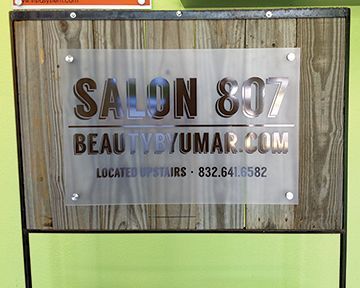 A sign for salon 807 beauty is sitting on a wooden table.