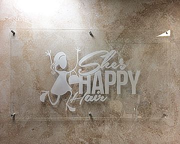 A sign that says `` she 's happy hair '' is hanging on a wall.