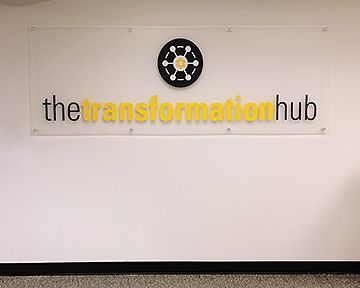 A white wall with a sign that says the transformation hub on it.