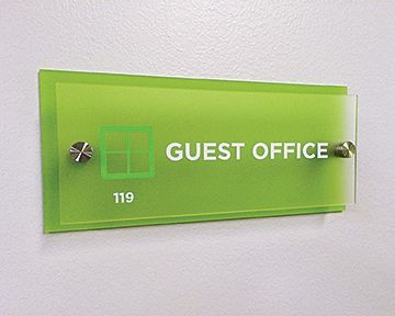 A green guest office sign on a white wall
