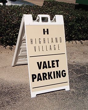 A valet parking sign is sitting on the side of the road.