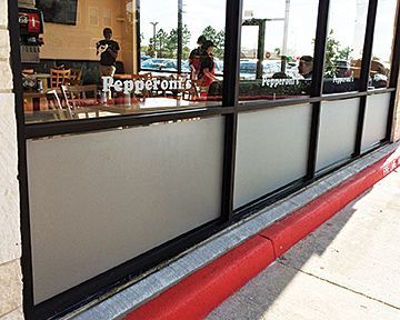 A pepperoni pizza restaurant with a lot of windows and a red curb.