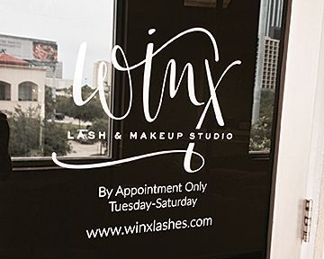 A sign for a lash and makeup studio is on a window.