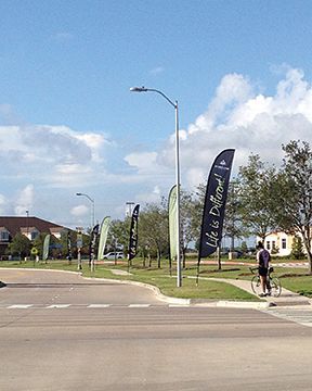 A person riding a bike down a street with flags that say life is different