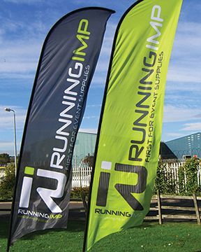 Two running imp flags are sitting on top of a lush green field.