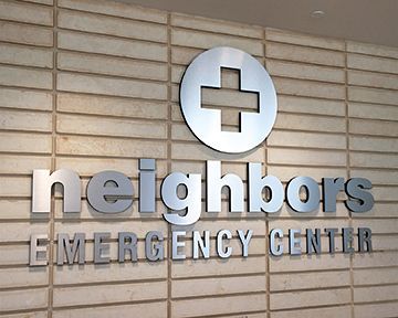 A sign for neighbors emergency center on a brick wall