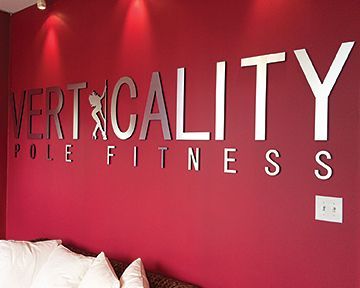 A red wall with verticality pole fitness written on it