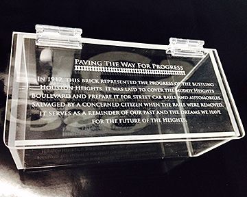 A clear acrylic box with a plaque on it that says paving the way for progress.