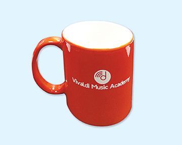 A red coffee mug that says vivaldi music academy on it