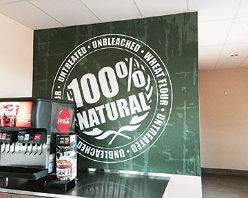 A coca cola machine is next to a sign that says 100 % natural