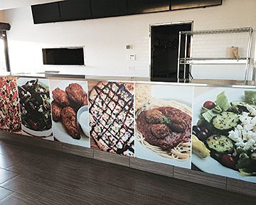 A restaurant counter with pictures of different types of food on it.