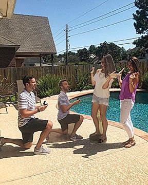 A man is proposing to a woman in front of a swimming pool.