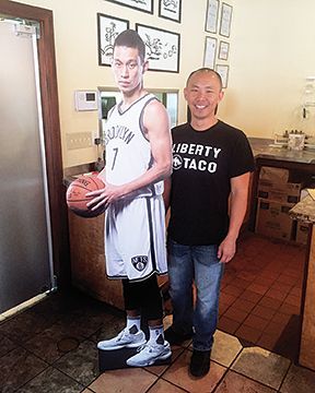 A man is standing next to a cardboard cutout of a basketball player holding a basketball.
