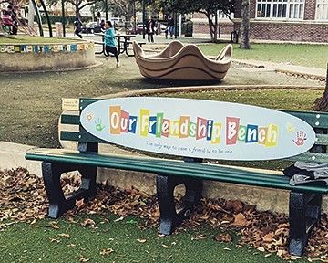 A park bench with a sign that says our friendship bench