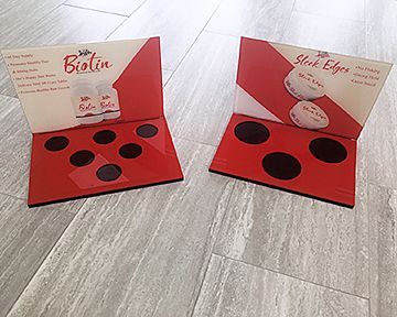 Two display stands for biotin are sitting on a wooden floor.