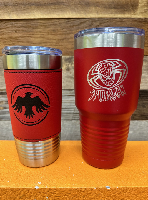 Two red stainless steel tumblers are sitting on a wooden table.