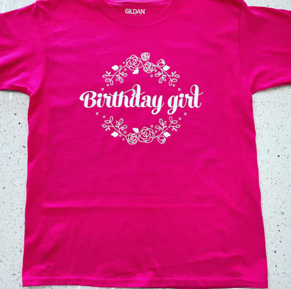 A pink shirt that says birthday girl on it.