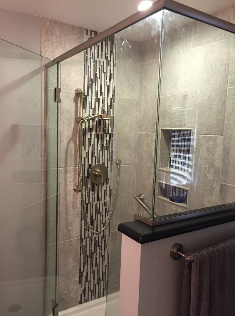 A bathroom with a walk in shower with a glass door.