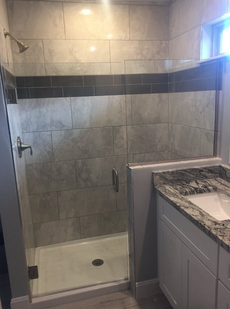 A bathroom with a walk in shower and a sink.