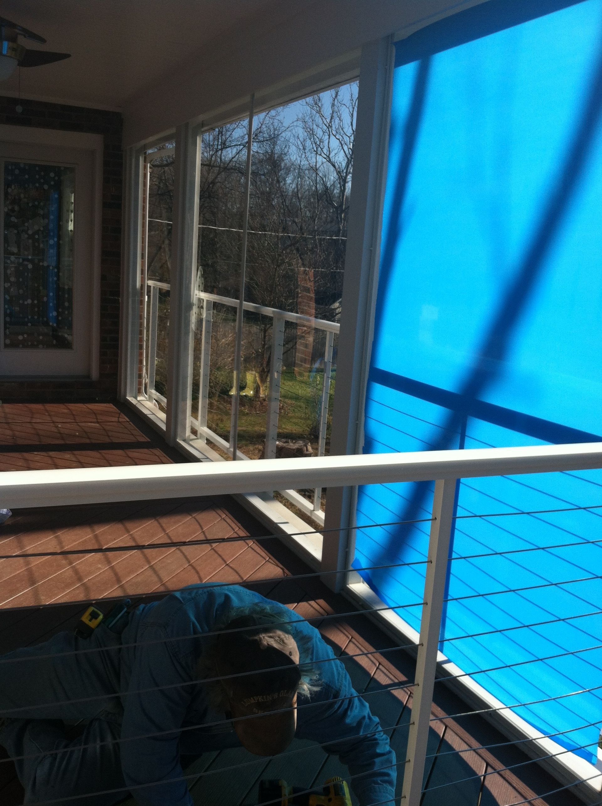 A blue screened in porch with a white railing