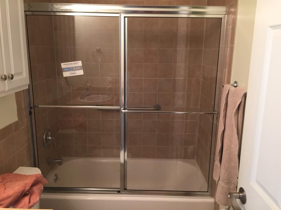A bathroom with a sliding glass shower door and a bathtub.