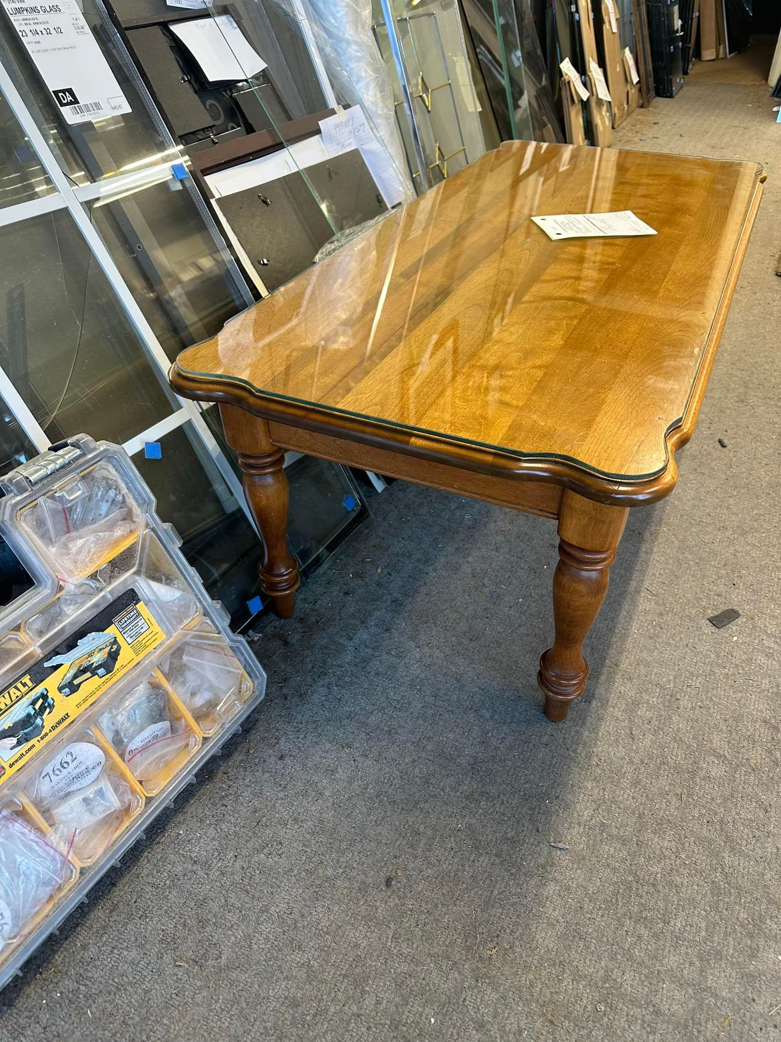 A wooden table with a glass top is sitting on a carpeted floor in a room.