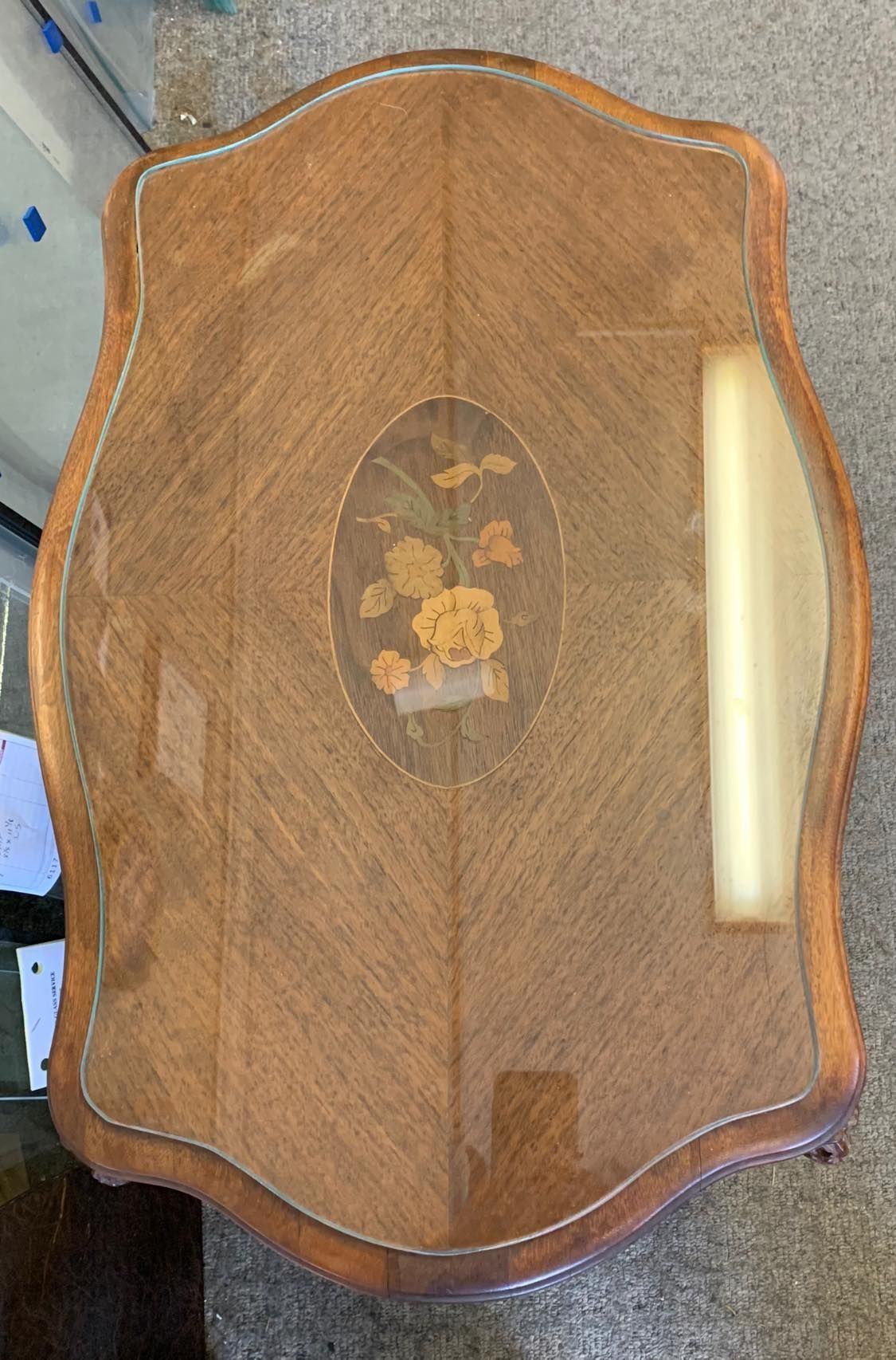 A wooden table with a glass top and a floral design on it.
