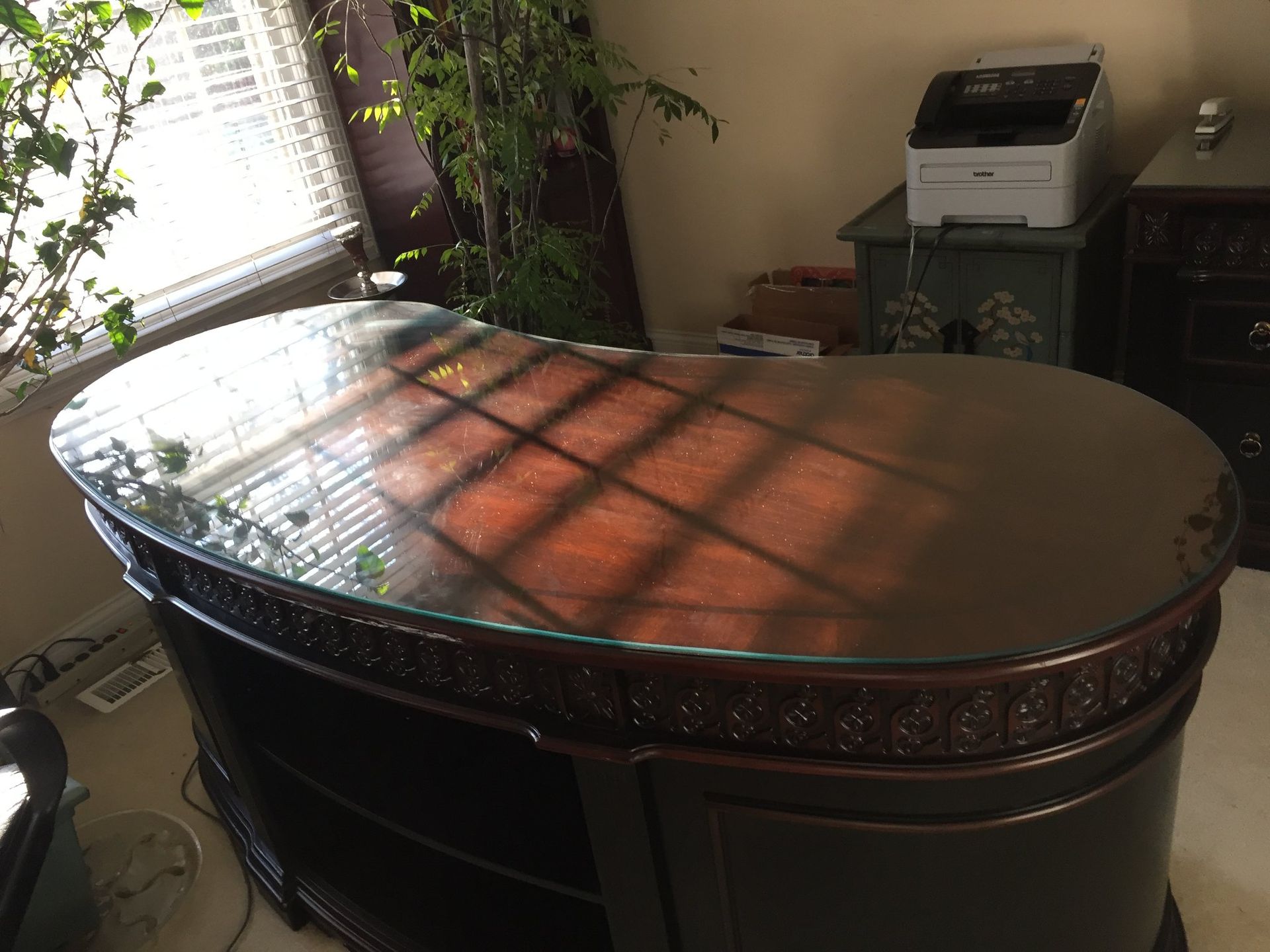 A desk with a glass top in a room next to a printer