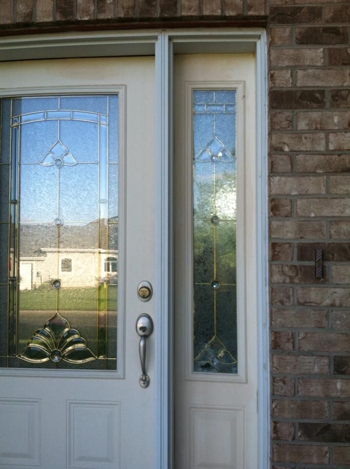 A white door with a stained glass window on a brick wall