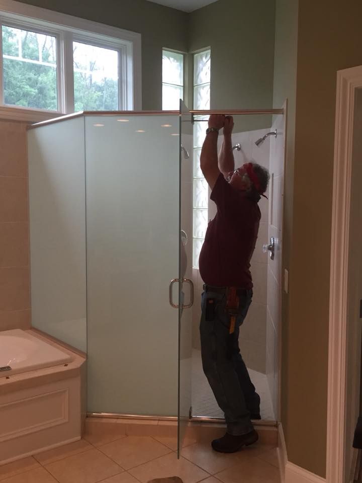 A man is installing a shower door in a bathroom.