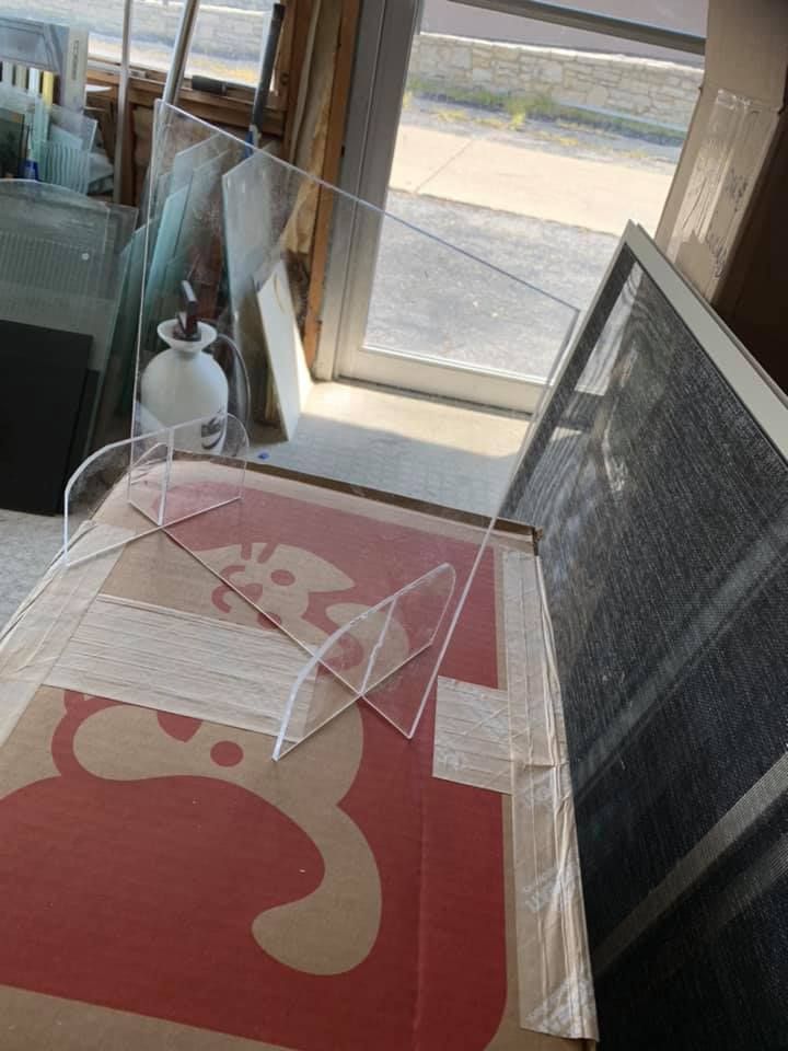 A clear acrylic shield is sitting on top of a cardboard box.