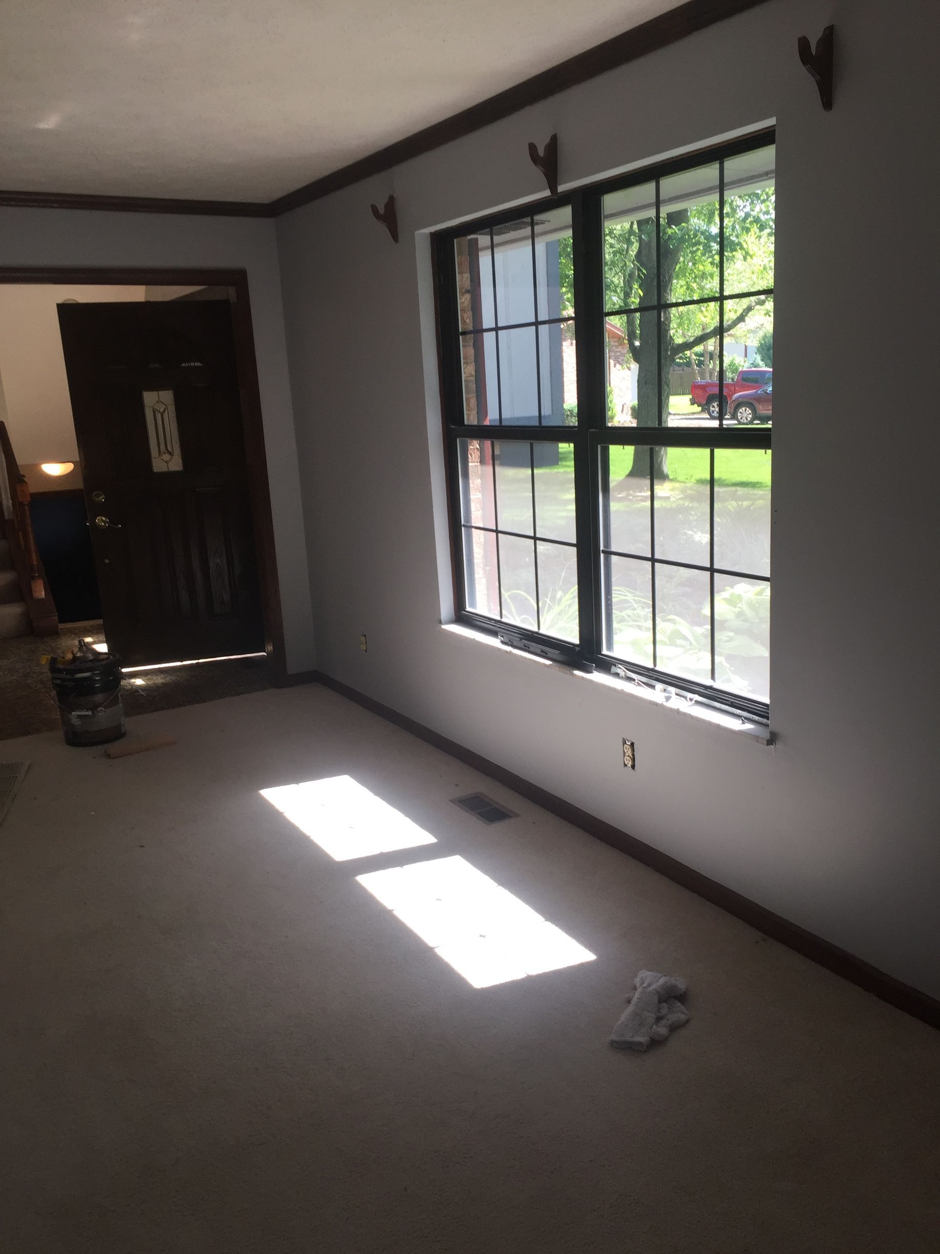 An empty living room with two windows and a door