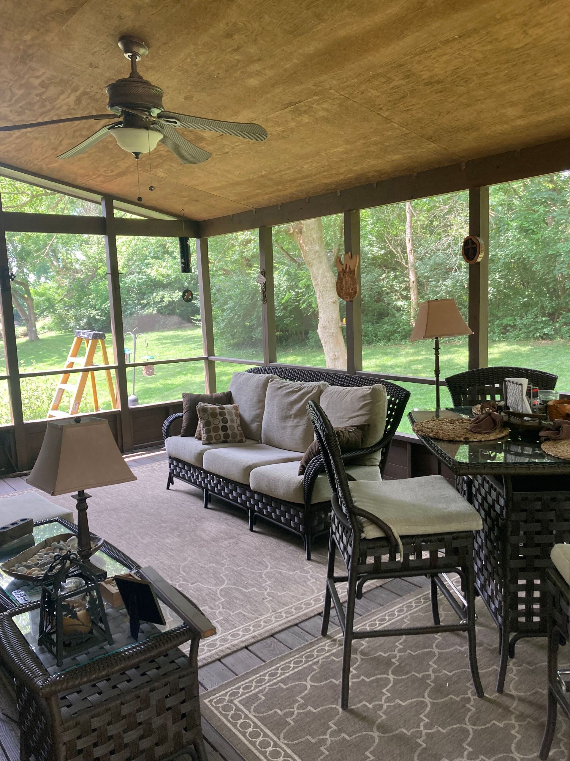 A screened in porch with furniture and a ceiling fan.