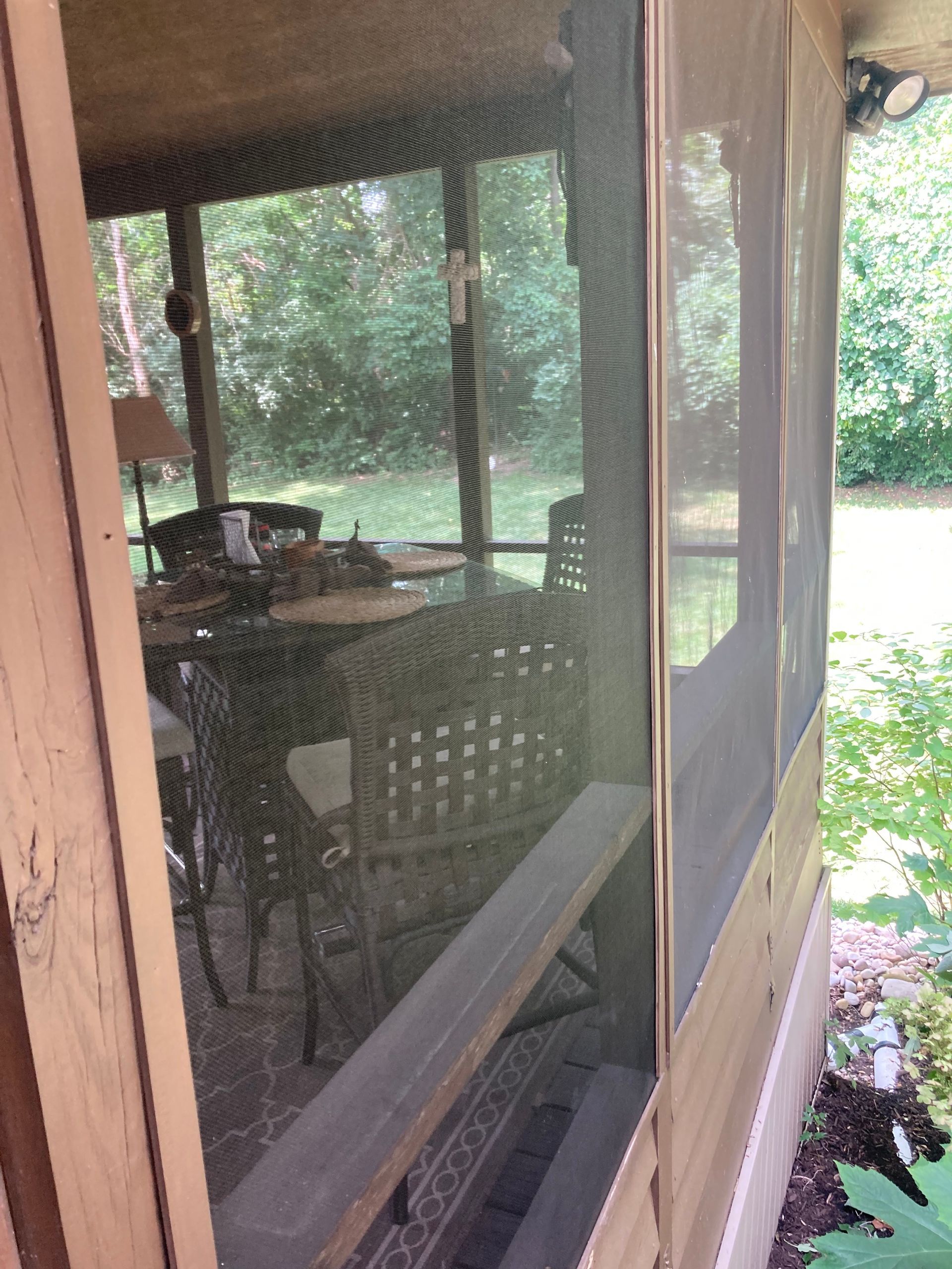 A screened in porch with a table and chairs in it.