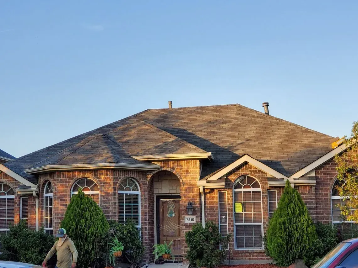Brick house with arched windows and a dark roof under a clear blue sky.