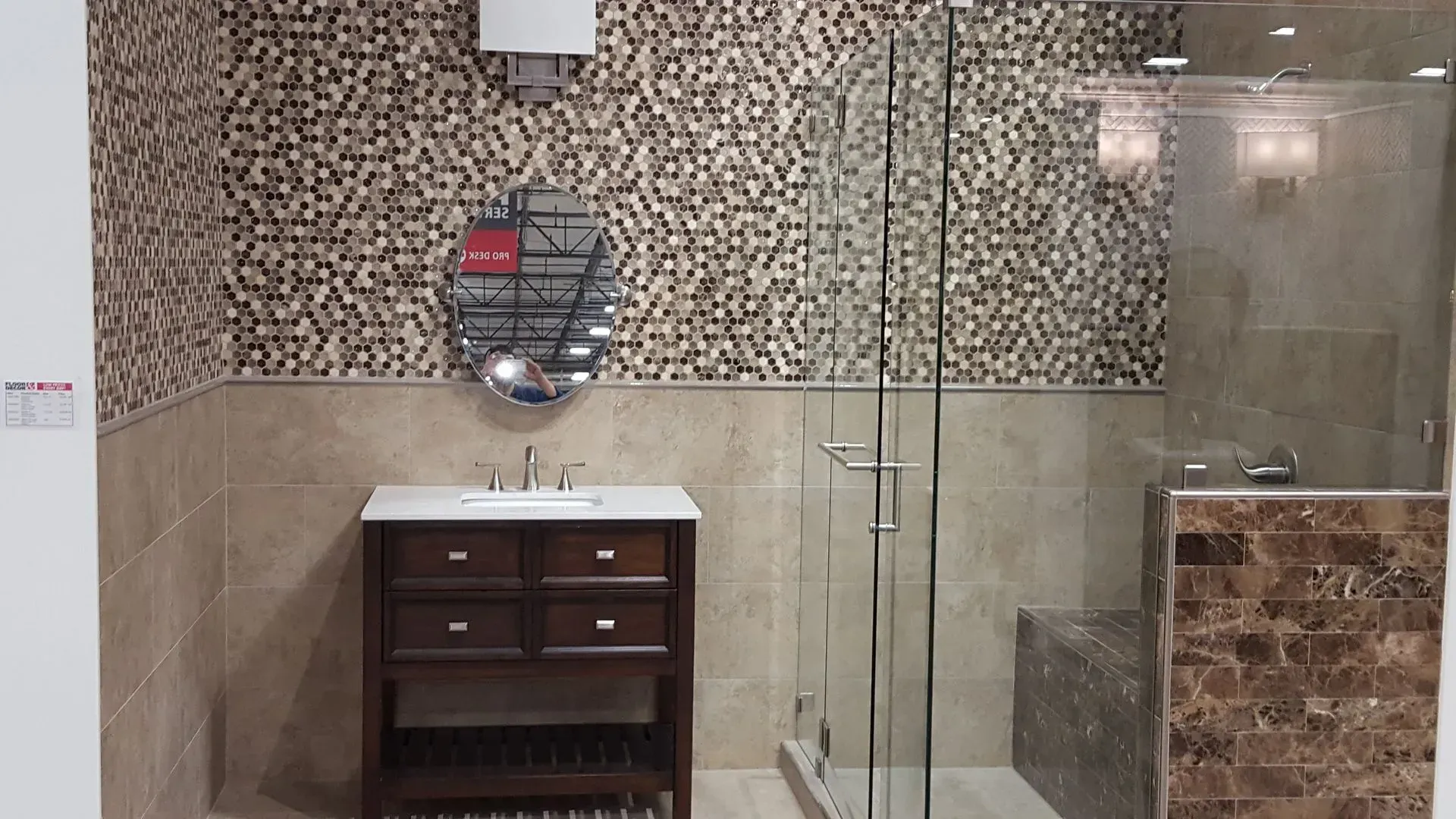 Bathroom with brown mosaic accent wall, dark wood vanity, glass shower, and beige tile.