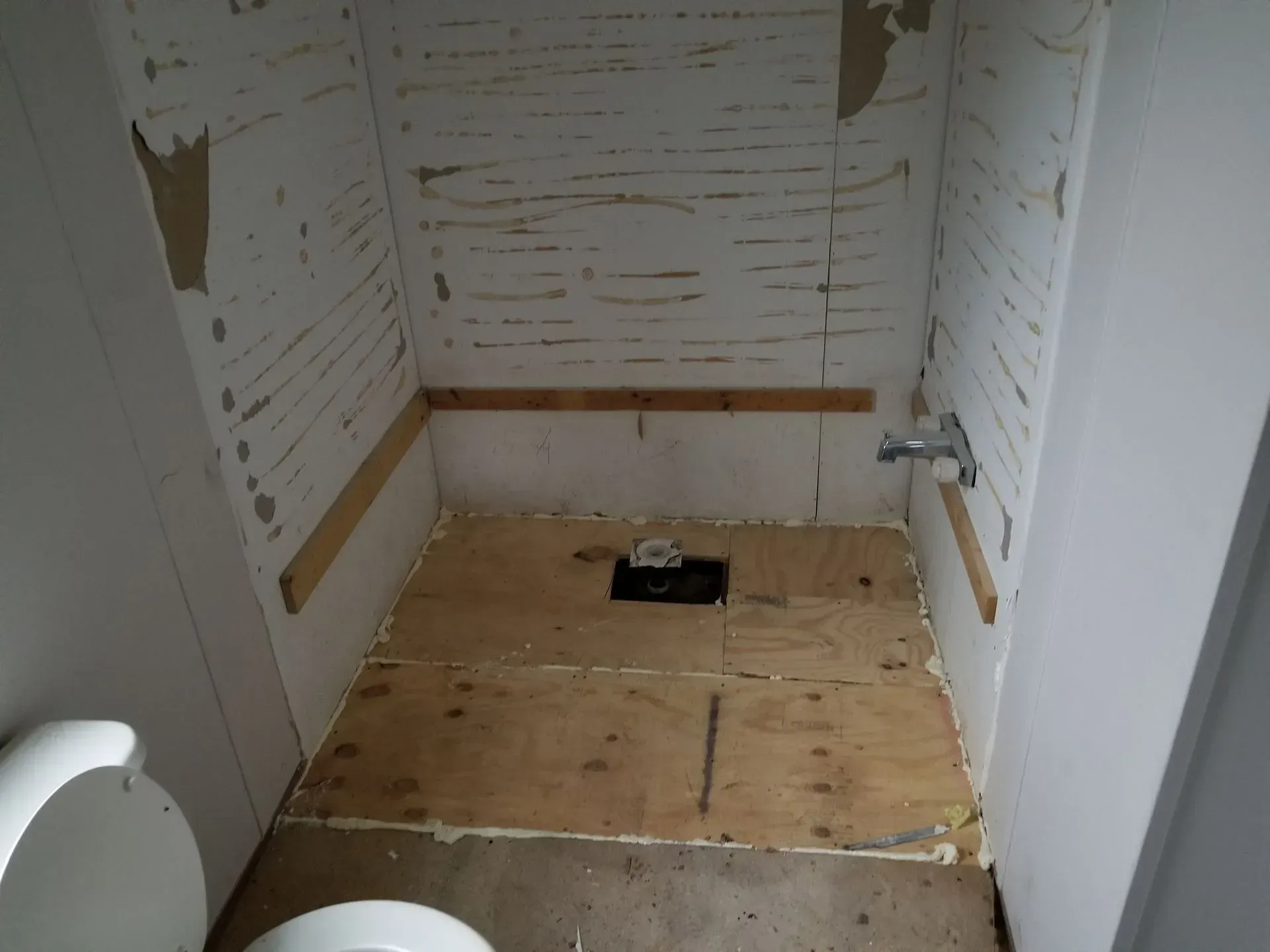 Small, unfinished bathroom with exposed wood flooring and walls, and toilet.