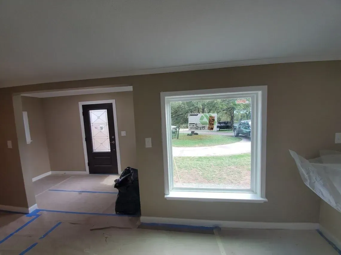 Interior view of a room with a window, doorway, and tan walls. There is a black trash bag.