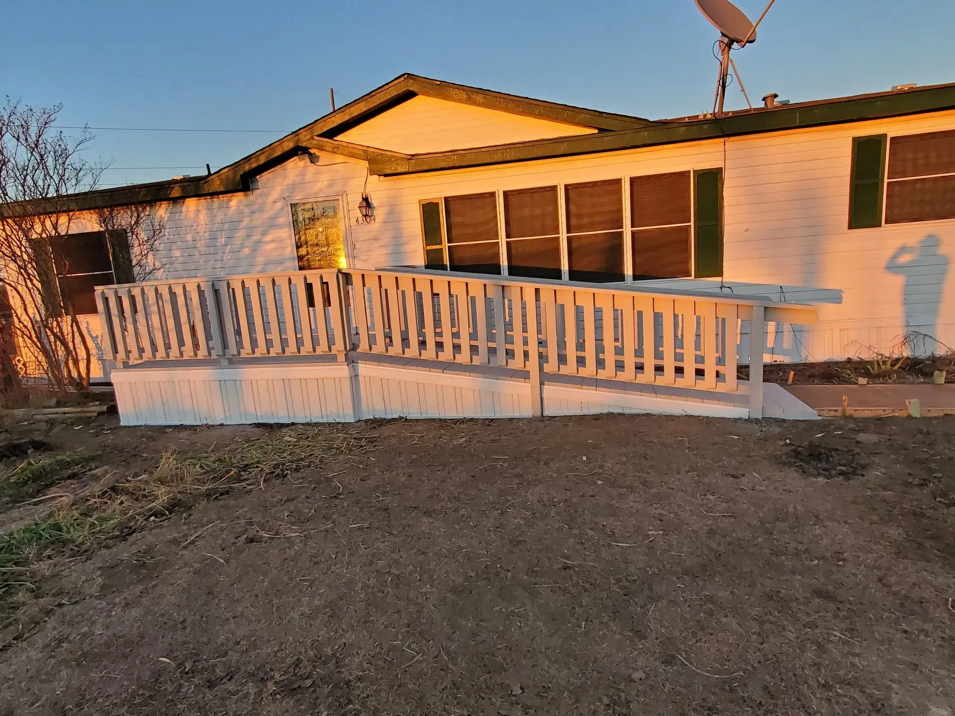 White house with a ramp for accessibility; the setting is outdoors with sunset light.